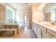 Modern bathroom featuring a glass shower, soaking tub, and double sink vanity with stone countertops at 7505 Woolf Way, Cumming, GA 30028