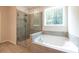 Modern bathroom features a soaking tub and large glass shower next to a bright window at 7505 Woolf Way, Cumming, GA 30028