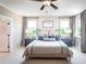 Well-lit bedroom with a ceiling fan, neutral colors, and windows overlooking nature at 7505 Woolf Way, Cumming, GA 30028