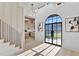 Bright foyer with a soaring ceiling, staircase, modern light fixture, and an arched steel and glass front door at 115 Nova Ln, Roswell, GA 30075