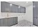 Laundry room features grey cabinets, stone countertop, and marble-patterned floors at 115 Nova Ln, Roswell, GA 30075