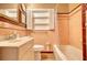 Retro pink bathroom with a bathtub, toilet, sink, and mirrored vanity at 177 Fairview Dr, Fairburn, GA 30213