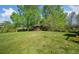 Expansive backyard featuring lush green grass, mature trees, and a storage shed at 4927 Bedell Ne Rd, Roswell, GA 30075