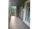 View of a covered front porch with wood flooring, white railings, door, and a window at 863 Fairwood Pointe Nw, Acworth, GA 30101