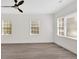 Bedroom with gray laminate wood floors, three windows, white walls, and a modern ceiling fan at 1728 Line St, Decatur, GA 30032