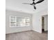Bedroom featuring gray laminate wood floors, three windows, white walls, and a modern ceiling fan at 1728 Line St, Decatur, GA 30032