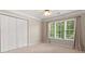 Bright bedroom featuring three windows, carpeted floors, and bi-fold door closet at 1420 Lockridge Dr, Cumming, GA 30041