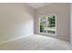An empty bedroom has neutral walls, carpet, and natural light from a large window at 660 Gran Heritage Way, Dacula, GA 30019