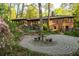 Brick home featuring an outdoor stone patio with seating surrounded by lush landscaping, trees and greenery at 1850 Winchester Trl, Brookhaven, GA 30341