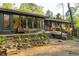 Rear exterior of home featuring expansive windows, a brick patio, and a tiered garden leading to a gravel terrace at 1850 Winchester Trl, Brookhaven, GA 30341