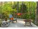 Relaxing backyard deck featuring a hammock, chair and fire pit, surrounded by mature trees at 1850 Winchester Trl, Brookhaven, GA 30341