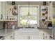 Bright kitchen features a farmhouse sink, stylish tile backsplash, and charming decor on the open shelving at 1850 Winchester Trl, Brookhaven, GA 30341
