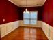 Dining room with rich red walls, white wainscoting, hardwood floors, and a large window for natural light at 445 Pintail Ct, Suwanee, GA 30024