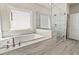 Luxurious bathroom features a soaking tub, marble tile, and glass enclosed shower at 627 Skytop Dr, Cumming, GA 30040