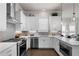 Well-lit kitchen boasts stainless appliances, herringbone backsplash, white cabinets and quartz countertops at 627 Skytop Dr, Cumming, GA 30040