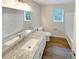 Bright bathroom featuring a double granite countertop vanity, matching toilet, and wood-look flooring at 8608 Creekview Ct, Douglasville, GA 30135