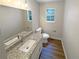 Neutral-toned bathroom featuring a granite countertop vanity, matching toilet, and wood-look flooring at 8608 Creekview Ct, Douglasville, GA 30135