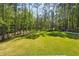 A fenced-in backyard with lush green grass surrounded by tall, mature trees at 1961 Flowering Dr, Grayson, GA 30017