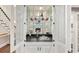 Stylish built-in bar cabinet with glass shelves, mirrored backsplash, sink, and accent lighting at 1183 Woods Ne Cir, Atlanta, GA 30324
