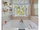 Bright bathroom featuring a soaking tub, open shutters, decorative shelves and a peaceful view at 826 Buffington Way, Canton, GA 30115
