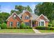 Charming red brick home with manicured lawn, mature trees, and traditional architectural details at 1740 Manhasset Pl, Atlanta, GA 30338