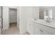 Bright bathroom featuring double sink vanity, white cabinetry, and a walk-in closet for ample storage space at 13579 Whitman Ln, Covington, GA 30014