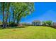 Large backyard featuring lush green grass, mature trees, and a sturdy wooden fence, ideal for outdoor activities and privacy at 10 Edgewater Ct, Covington, GA 30016