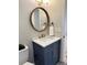 Bathroom with blue vanity, marble countertop, gold faucet, and round mirror at 6213 Marbut Farms Chase, Lithonia, GA 30058