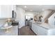 Well-lit kitchen with stainless steel appliances, white cabinetry, granite counters, and a staircase nearby at 166 Aster Avenue, Locust Grove, GA 30248