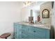 Bright bathroom with dual sinks set in a granite countertop with teal cabinets and a vintage mirror at 3665 Essex Ave # 28, Atlanta, GA 30339
