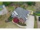 Aerial view of a two-story home with brick and siding, a large driveway, mature trees, and lush landscaping at 204 Maple Creek Chase, Woodstock, GA 30188