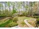 Lush backyard featuring mature trees, landscaping, and a charming walking bridge at 204 Maple Creek Chase, Woodstock, GA 30188