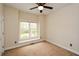 Bright, carpeted bedroom featuring a ceiling fan and a window with a view of the backyard at 204 Maple Creek Chase, Woodstock, GA 30188