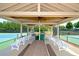 Covered deck with ceiling fan and seating near outdoor tennis court with green and blue surface at 204 Maple Creek Chase, Woodstock, GA 30188