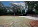 View of a backyard with a three sided metal shelter and gravel driveway and a privacy fence at 2533 Whispering Pines Dr, Grayson, GA 30017