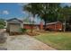 Backyard view of a red brick home with a detached one-car garage, and a gravel driveway at 2533 Whispering Pines Dr, Grayson, GA 30017