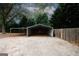 View of a backyard with a three sided metal shelter and gravel driveway and a privacy fence at 2533 Whispering Pines Dr, Grayson, GA 30017