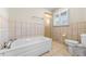Bathroom with a bathtub, tiled walls, window with shutters, and a toilet at 3325 N Embry Cir, Atlanta, GA 30341