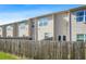 A backyard featuring a wooden fence, well-maintained lawn, and view of the rear facade of the homes with visible windows at 6415 Shalks Crossing Dr, Lithonia, GA 30058