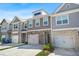 View of townhome exteriors with stone accents, garages, and well-maintained landscaping at 6415 Shalks Crossing Dr, Lithonia, GA 30058