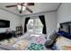 Inviting bedroom with a ceiling fan, window view, and a dresser with a television at 320 Hillside Manor Dr, Sugar Hill, GA 30518