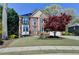 Inviting two-story brick home with a manicured lawn, complemented by vibrant landscaping and charming details at 320 Hillside Manor Dr, Sugar Hill, GA 30518