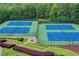 Aerial view of tennis courts with lush greenery, offering a great recreational amenity for residents at 320 Hillside Manor Dr, Sugar Hill, GA 30518