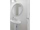 Close-up of a pedestal sink in a bathroom with a round mirror and silver hardware at 4185 Waterford Dr, Suwanee, GA 30024