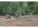 Community playground nestled in a wooded area, featuring slides, climbing structures, and picnic tables at 4185 Waterford Dr, Suwanee, GA 30024