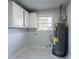 Compact utility room with a modern water heater, white tile flooring, a window, and storage cabinets at 3036 Crabapple Cir, Decatur, GA 30034