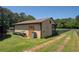 Side exterior of the barn featuring tan color, a metal roof, and a small door next to a black fence at 5187 Parkview Rd, Social Circle, GA 30025