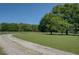 Scenic view of the lush property featuring a long, winding gravel driveway, mature trees and green grass at 5187 Parkview Rd, Social Circle, GA 30025