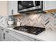 Close-up of a modern gas cooktop with designer backsplash and stainless steel microwave at 530 Payne Rd, Woodstock, GA 30188
