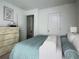 Bright bedroom features a neatly made bed with a teal blanket, neutral walls, and a wooden dresser at 3333 Tarian Way, Decatur, GA 30034